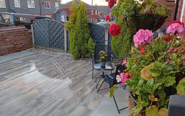 a cozy outdoor patio with flowering plants chairs and a wooden fence providing a peaceful space for relaxation in a sunlight setting perfect for two